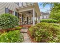 Inviting front porch with seating, lush landscaping, stone pathway, and classic home exterior at 117 N Mulberry St, Statesville, NC 28677