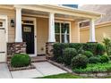 Inviting front porch with stone pillars, manicured bushes, and stylish black front door at 203 Rustling Waters Dr, Mooresville, NC 28117