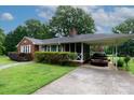 An attractive brick home featuring a carport, screened-in porch, and lush greenery at 205 Hillcrest Ave, Rock Hill, SC 29732