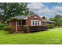 A side view of a red brick home with shuttered windows and manicured landscaping at 205 Hillcrest Ave, Rock Hill, SC 29732