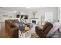 Spacious living room with dark brown furniture, a fireplace, and plenty of natural light at 3951 Tersk Dr, Midland, NC 28107