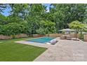 Relax in this backyard oasis with an inground pool, stone patio, and lush landscaping for outdoor enjoyment at 6946 Woodstock Dr, Charlotte, NC 28210