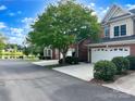 Charming brick two-story home featuring a well-manicured lawn, tree, and a scenic view of the community pond at 705 Congressional Ln, Fort Mill, SC 29708