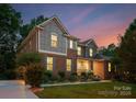 Two-story home displaying brick and stone accents, side-entry garage, and mature landscaping at 7798 Sand Trap Ln, Stanley, NC 28164