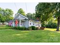 Quaint single-story home with a well-manicured lawn, front porch with rocking chairs, and mature trees at 100 S Rudisill Ave, Cherryville, NC 28021