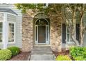 Close-up of a beautiful front door with stone archway, steps, and tasteful landscaping at 10927 Thornhill Club Dr, Charlotte, NC 28277
