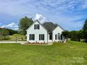 Desirable white brick home with black shutters on a large, grassy lawn and landscaped yard at 116 Eve Ash Ln, Mooresville, NC 28115