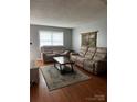 Cozy living room featuring comfortable seating, a stylish rug, and warm wood floors at 1300 Larchmont Pl, Salisbury, NC 28144