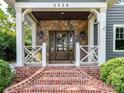 Inviting front porch with stone accents, white columns, and brick steps at 2526 Sherwood Ave, Charlotte, NC 28207