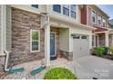 Close-up of a townhouse with stone accents, a blue door with wreath, and an attached garage at 318 Willow Wood Ct, Matthews, NC 28104