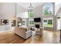 Bright living room featuring hardwood floors, high ceilings, fireplace, modern lighting fixture, and neutral decor at 3324 Greenhurst Dr, Matthews, NC 28104