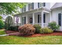 Charming front porch with a decorative wreath, black shutters, and lush landscaping at 506 Academy St, McAdenville, NC 28101