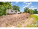 An eye-level exterior shows the rear of the home with an additional red building and freshly graded soil at 5090 Beaver Dam Way, Bessemer City, NC 28016