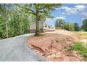 An eye-level exterior shows the left side of the home with an extra long driveway and freshly graded soil at 5090 Beaver Dam Way, Bessemer City, NC 28016