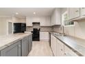 Modern kitchen featuring stainless steel sink, black appliances, and gray kitchen island at 5090 Beaver Dam Way, Bessemer City, NC 28016