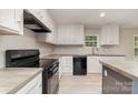Bright kitchen features white cabinetry, black appliances, and a functional layout at 5090 Beaver Dam Way, Bessemer City, NC 28016
