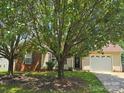 Welcoming home with attached garage, showcasing a well-maintained lawn and mature trees at 6902 Vernon Wood Ln, Charlotte, NC 28262