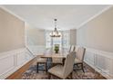 Bright dining room featuring wainscoting, a large window, and a decorative chandelier above the wooden table at 7810 Leisure Ln, Huntersville, NC 28078