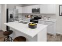 Modern kitchen showcases white cabinets, stainless appliances, a large quartz island with barstool seating, and sleek fixtures at 1202 Elm Forest Ln, China Grove, NC 28023