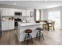 Bright kitchen featuring white cabinets, stainless steel appliances, a quartz countertop island with seating, and adjacent dining area at 1202 Elm Forest Ln, China Grove, NC 28023