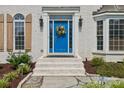 Close-up of a blue front door with a decorative wreath, sidelights, and stone steps, framed by manicured landscaping at 122 Ringneck Trl, Mooresville, NC 28117