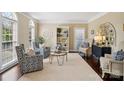 Bright living room with neutral tones, patterned chairs, area rug, white bookshelf, and large windows at 122 Ringneck Trl, Mooresville, NC 28117