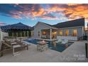 Inviting backyard pool featuring in-pool loungers, a fire pit, and an umbrella-shaded dining area for relaxation at 12615 Es Draper Dr, Huntersville, NC 28078