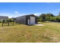 Large metal barn with a white door and concrete pad, surrounded by a green pasture at 15020 Ranson Rd, Huntersville, NC 28078