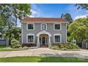 Attractive two-story home with gray siding, a red tile roof, professional landscaping, and a gated driveway at 1619 Providence Rd, Charlotte, NC 28207