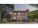 Beautiful home at dusk with gray siding and a red tile roof with professional landscaping and a gated driveway at 1619 Providence Rd, Charlotte, NC 28207