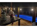 Relaxing outdoor deck with table and chairs overlooking a sparkling blue swimming pool at night at 1673 Beleek Ridge Ln, Clover, SC 29710