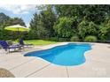 Backyard featuring a private pool with a concrete deck and mature landscaping at 175 Turnberry Ln, Mooresville, NC 28117