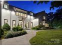 Night view of an elegant white brick home with landscaped front yard and a stone walkway to the entrance at 2215 Cortelyou Rd, Charlotte, NC 28211