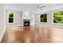 Bright living room featuring a fireplace, hardwood floors, large windows, and a ceiling fan at 2857 Scarborough Ct, Gastonia, NC 28054