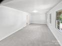 A carpeted living room with a view of the outdoors through two windows and a doorway in the background at 302 Melinda Ave, Kannapolis, NC 28083