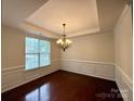 Elegant dining room featuring a tray ceiling, hardwood floors, wainscoting, and a stylish chandelier at 1304 Ridge Haven Rd, Waxhaw, NC 28173