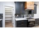Modern kitchen boasts sleek dark cabinets, wooden range hood, and marble backsplash with stainless steel oven at 1524 Enochville Rd, Kannapolis, NC 28081