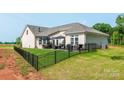 Beautiful backyard features a well-manicured lawn, black metal fence, and outdoor patio with seating and grill at 3006 Constitution Ln, Gastonia, NC 28056