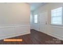 Bright foyer featuring wainscoting, luxury vinyl flooring, and a white front door flanked by two windows at 524 Hullview Vis, Monroe, NC 28110