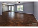Spacious living room featuring wood-look flooring, modern ceiling fan, and large windows at 7623 Monarch Birch Ln, Charlotte, NC 28215