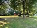 Large, well-maintained backyard with mature trees and two outbuildings at 8616 Fallsdale Dr, Charlotte, NC 28214