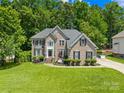 Stately two-story brick home featuring lush lawn, landscaped yard, and mature trees under a sunny sky at 122 Laurel Glen Dr, Mooresville, NC 28115