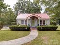 Inviting home with a red metal roof, beautifully landscaped front yard, and a welcoming front porch at 1614 Linwood Rd, Gaston, NC 28052
