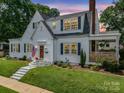 Charming two-story home with white siding, black shutters, an American flag and manicured lawn at dusk at 329 E Congress St, Lincolnton, NC 28092