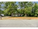Quaint light yellow home with a covered porch, framed by mature shade trees at 39 Selma Dr, Mooresville, NC 28115