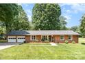 Charming brick home with an attached two-car garage, lush green lawn, and mature trees at 400 S Westover Dr, Monroe, NC 28112
