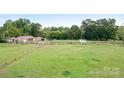 Wide shot showing an expansive green field, fenced in areas and various outbuildings at 4026 Biggerstaff Rd, Maiden, NC 28650