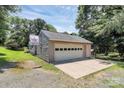 Spacious two-car garage with a wide driveway, offering ample parking and storage, surrounded by mature trees at 4104 Pebblebrook Sw Cir, Concord, NC 28027