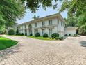 A classic white home displays an elegant exterior, complemented by a circular driveway and lush greenery at 4300 Cameron Oaks Dr, Charlotte, NC 28211