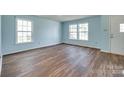 Bright living room with hardwood floors, featuring two large windows and a white door at 672 Carybrook Ct, York, SC 29745